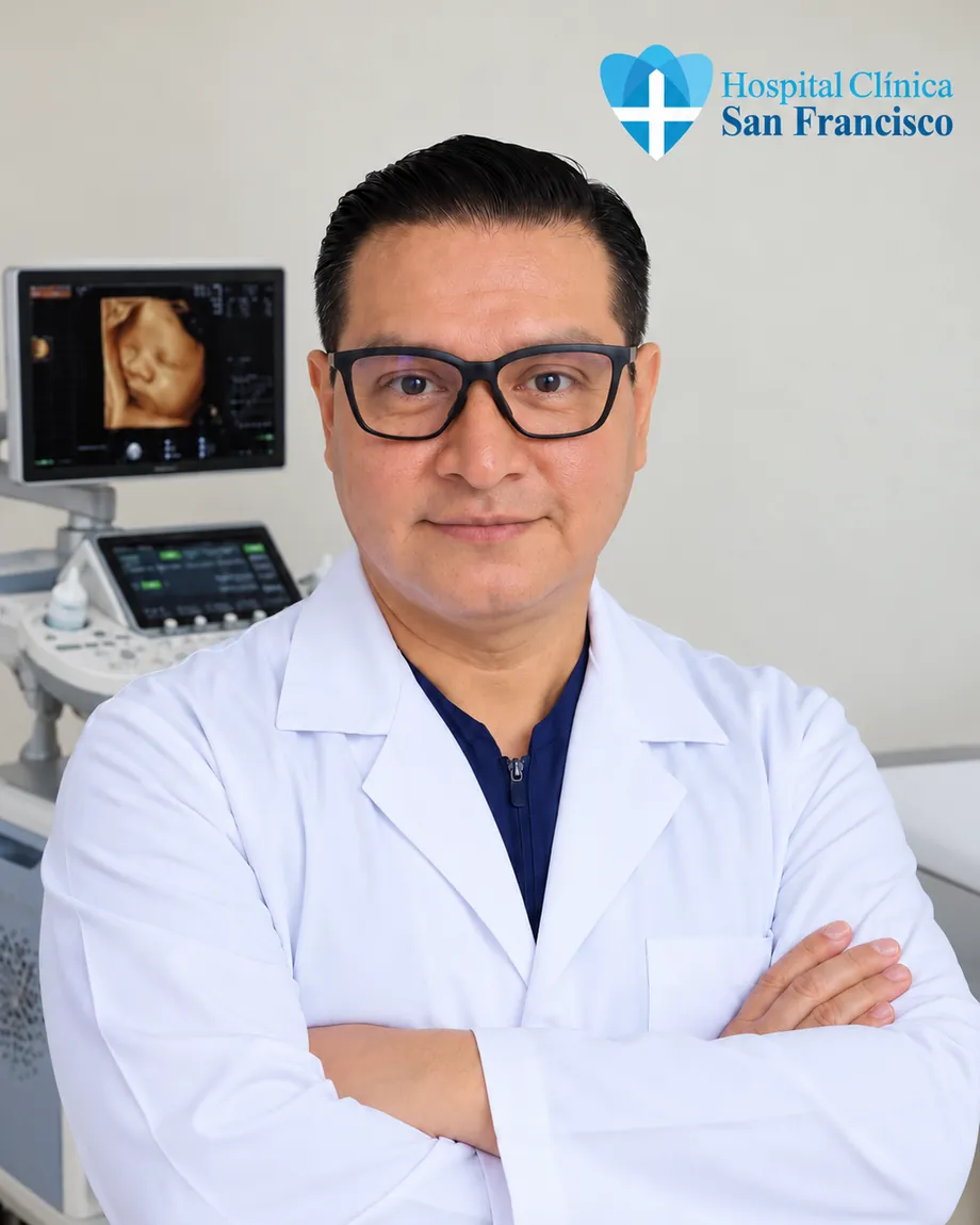 Retrato del Dr. Giovanny Colcha con bata blanca en su consultorio, junto al ecógrafo